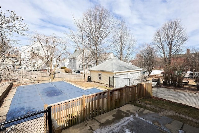 exterior space featuring a fenced in pool, a residential view, a fenced backyard, an outdoor structure, and a garage