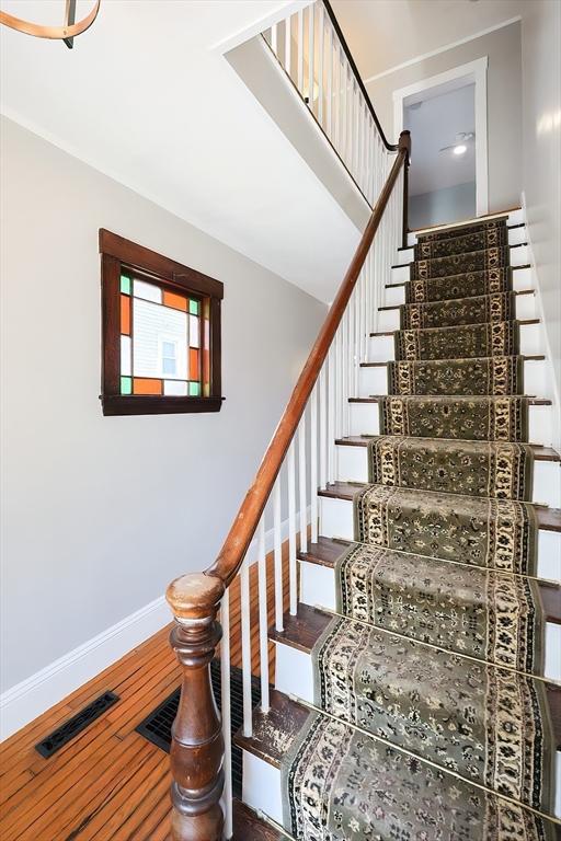 stairs with visible vents, baseboards, and wood finished floors