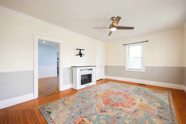 unfurnished living room with a fireplace, crown molding, wood finished floors, and baseboards