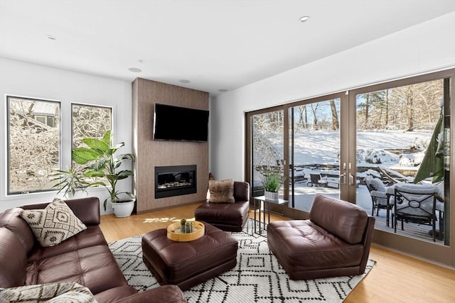 living room with light hardwood / wood-style floors, a tile fireplace, and french doors