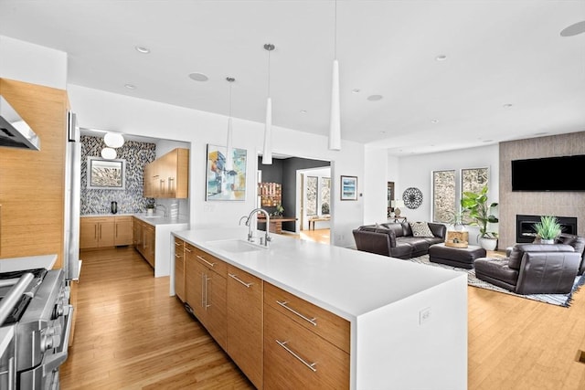 kitchen with a spacious island, stainless steel range, a fireplace, sink, and backsplash