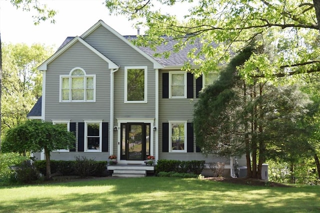 rear view of house with a lawn and roof with shingles