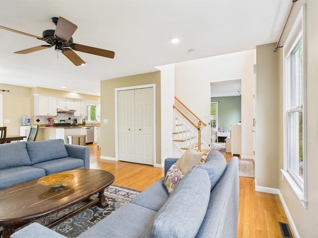living area featuring stairs, light wood-type flooring, healthy amount of natural light, and recessed lighting