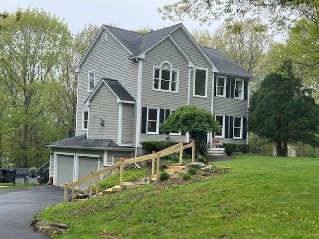 colonial inspired home featuring a garage, driveway, and a front lawn