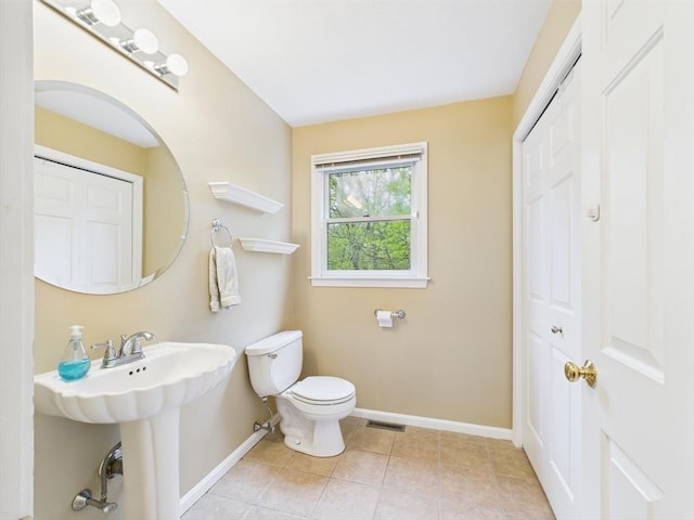 bathroom with toilet, baseboards, tile patterned floors, and a sink