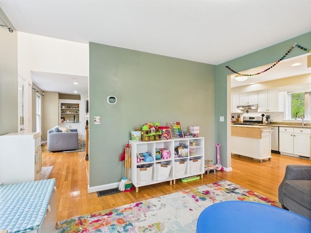 rec room with light wood-style floors, baseboards, and a sink