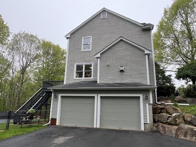 view of side of property featuring driveway, stairs, and an attached garage