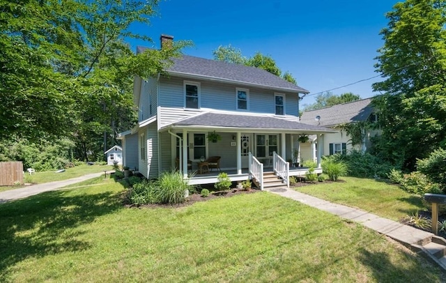 traditional home with a front lawn, covered porch, and a chimney