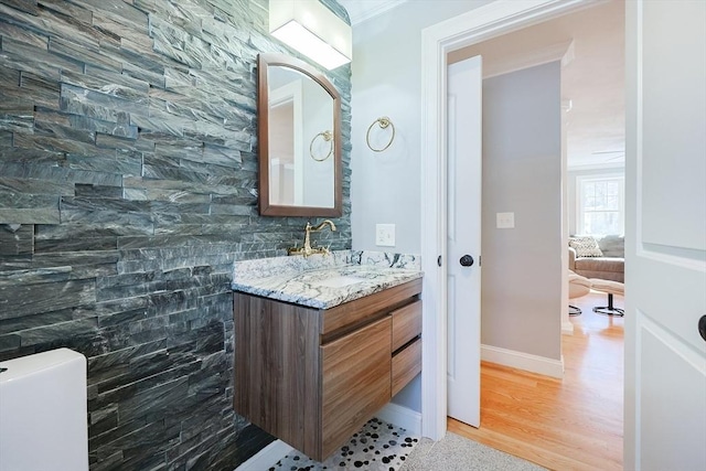 bathroom with crown molding, baseboards, wood finished floors, and vanity