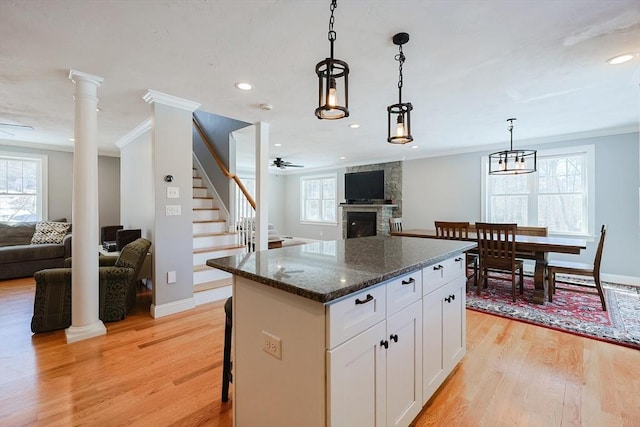 kitchen featuring open floor plan, ornamental molding, light wood-type flooring, and a center island