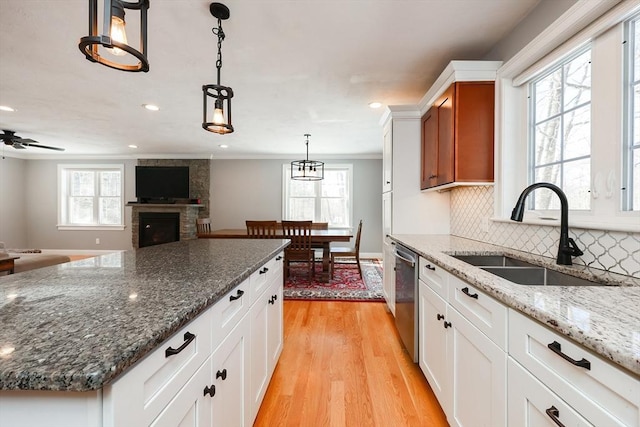 kitchen with tasteful backsplash, dishwasher, crown molding, light wood-style floors, and a sink