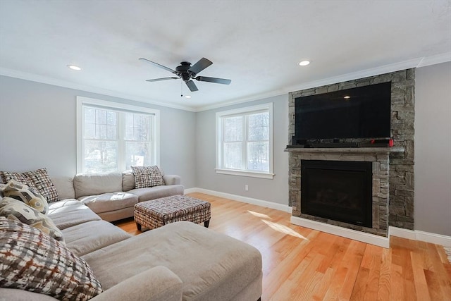 living room featuring baseboards, a stone fireplace, wood finished floors, and crown molding