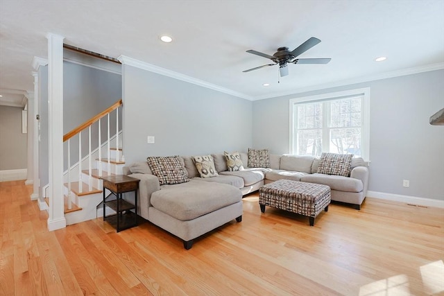 living room with light wood-style flooring, ornamental molding, ceiling fan, baseboards, and stairs