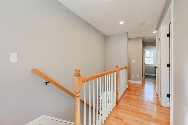 hallway featuring attic access, baseboards, an upstairs landing, light wood-type flooring, and recessed lighting