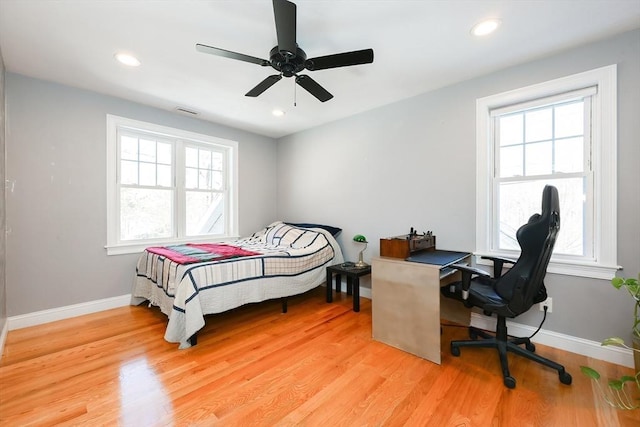 bedroom with multiple windows, light wood-style flooring, and baseboards