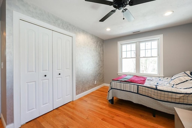 bedroom with light wood finished floors, a closet, recessed lighting, and baseboards