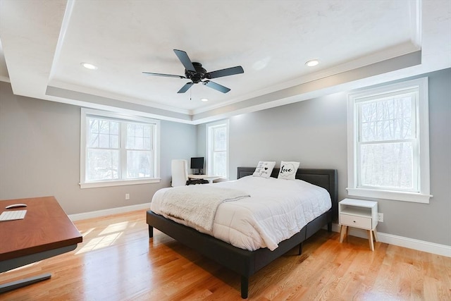 bedroom featuring light wood-style flooring, recessed lighting, baseboards, ornamental molding, and a tray ceiling