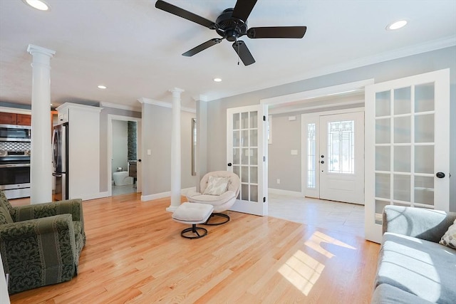 living area featuring decorative columns, crown molding, and french doors