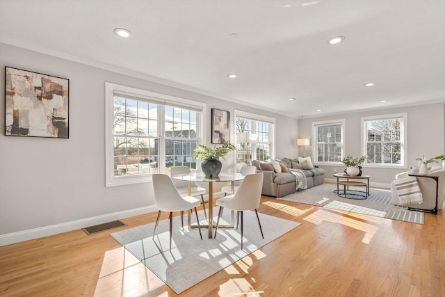 dining space featuring crown molding and light hardwood / wood-style floors