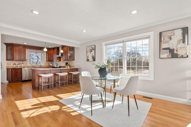 dining space featuring ornamental molding and light wood-type flooring