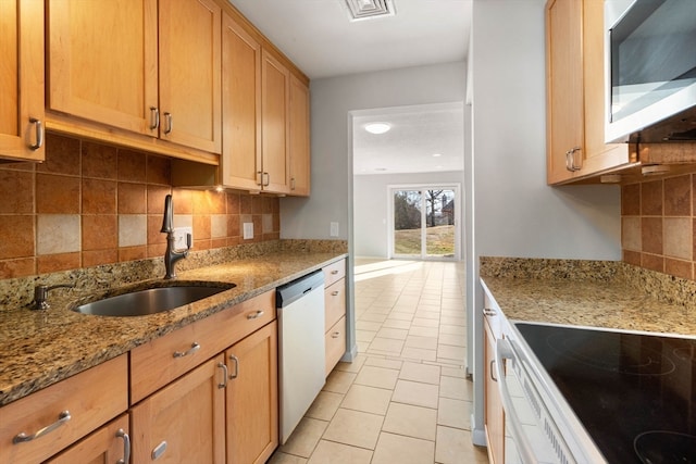 kitchen with light tile patterned floors, stainless steel appliances, light stone counters, and sink