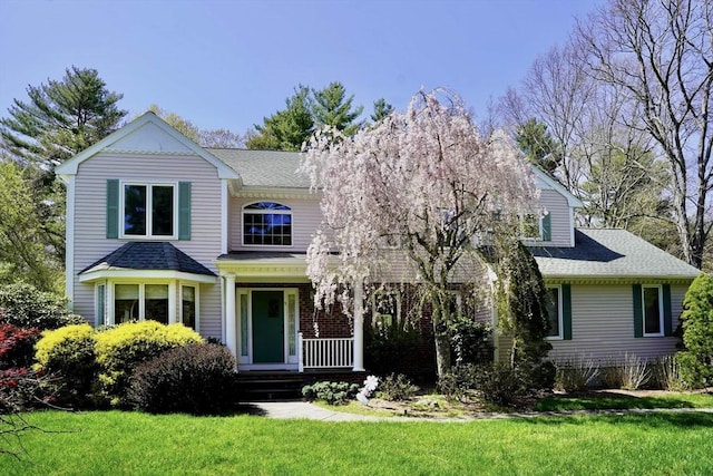 view of front of home with a front yard, a porch, and a shingled roof