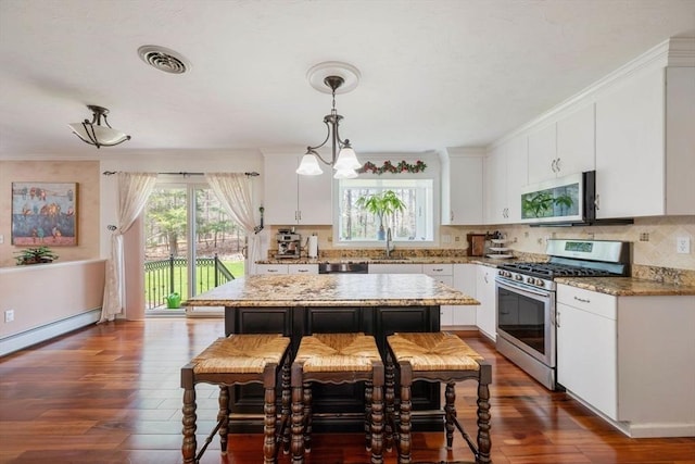 kitchen featuring appliances with stainless steel finishes, dark wood finished floors, white cabinetry, decorative backsplash, and hanging light fixtures