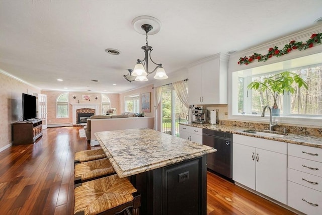 kitchen with a sink, dishwasher, crown molding, white cabinetry, and healthy amount of natural light