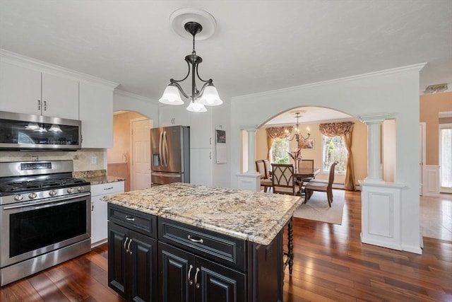 kitchen featuring appliances with stainless steel finishes, arched walkways, a chandelier, dark cabinetry, and dark wood finished floors