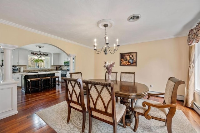 dining room with decorative columns, a chandelier, arched walkways, wood finished floors, and crown molding