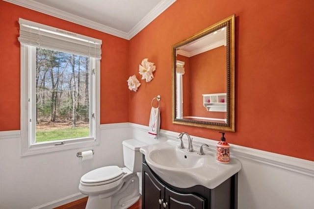 half bathroom with toilet, vanity, and ornamental molding