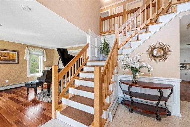 staircase with wood finished floors and crown molding