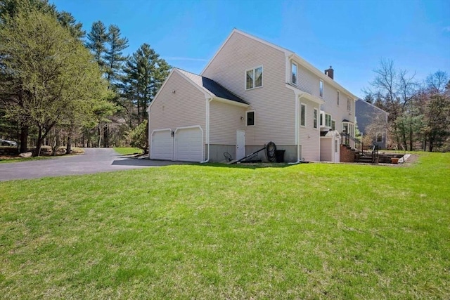 view of side of home featuring driveway, a chimney, a yard, stairway, and a garage
