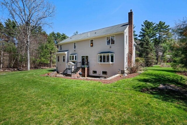 rear view of house with a chimney, a yard, and entry steps