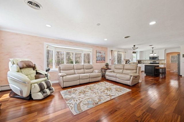 living room with healthy amount of natural light, dark wood finished floors, ornamental molding, recessed lighting, and a chandelier