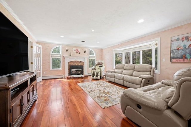 living area with plenty of natural light, crown molding, a baseboard radiator, light wood-style floors, and a brick fireplace