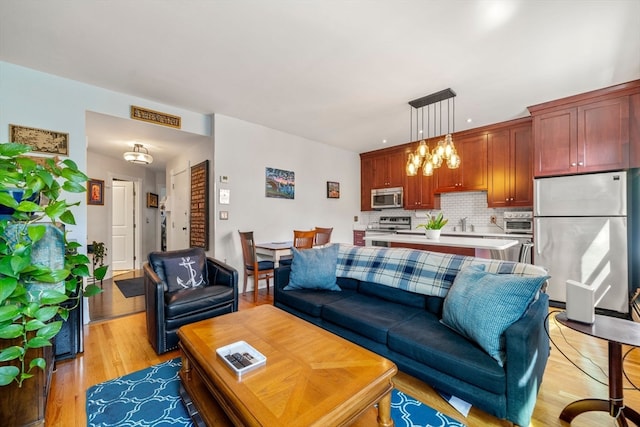 living room with a notable chandelier, light wood-type flooring, and sink