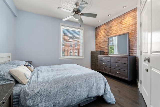 bedroom with brick wall, dark wood-type flooring, multiple windows, and ceiling fan