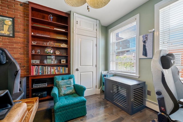 living area featuring baseboard heating, dark hardwood / wood-style floors, and ceiling fan