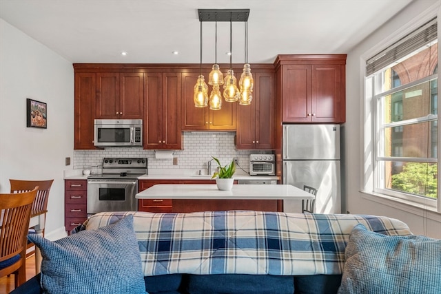 kitchen featuring decorative backsplash, appliances with stainless steel finishes, plenty of natural light, and decorative light fixtures