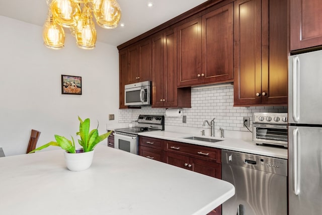 kitchen with stainless steel appliances, hanging light fixtures, sink, and tasteful backsplash