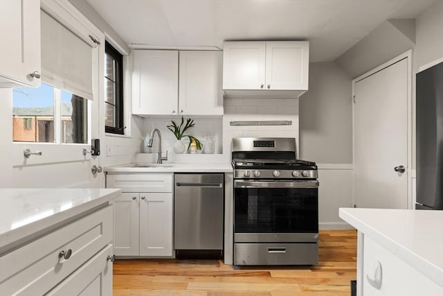 kitchen featuring white cabinets, sink, stainless steel appliances, and light hardwood / wood-style flooring