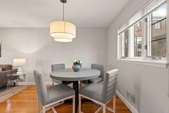 dining area featuring hardwood / wood-style floors and wooden walls