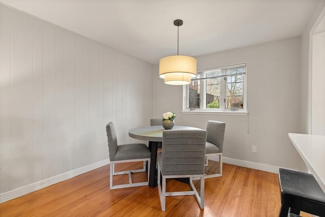 dining space with wood walls and light hardwood / wood-style floors