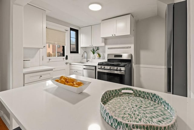 kitchen featuring white cabinets, stainless steel appliances, tasteful backsplash, and sink