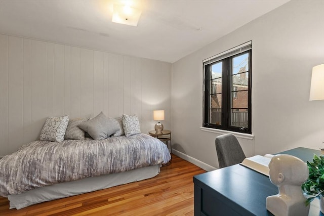 bedroom with light wood-type flooring and wooden walls