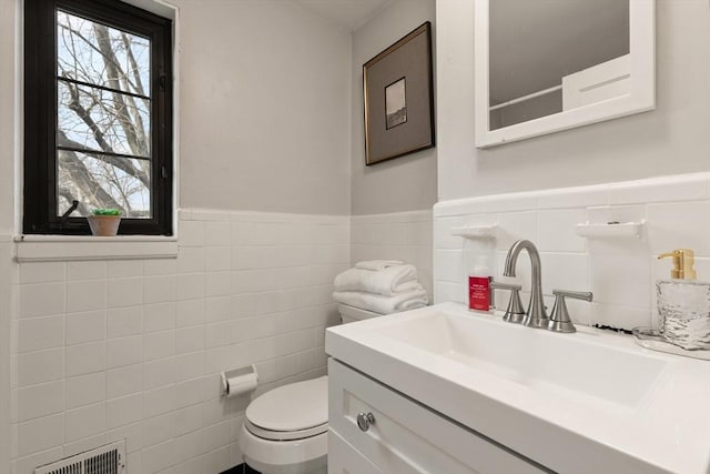 bathroom with vanity, toilet, and tile walls