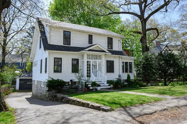 view of front facade featuring an outbuilding, entry steps, a front yard, a shingled roof, and a garage