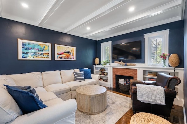 living room featuring beam ceiling, wood finished floors, ornamental molding, and a fireplace