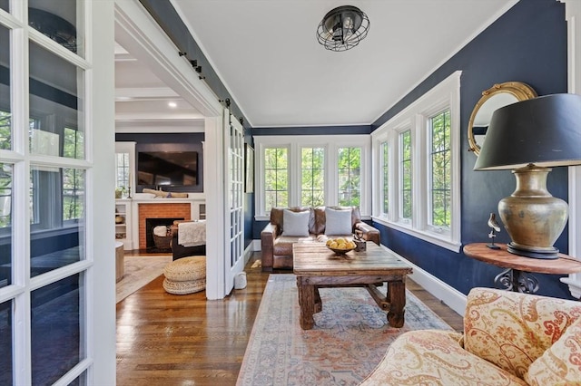 sunroom / solarium featuring crown molding, wood finished floors, and baseboards